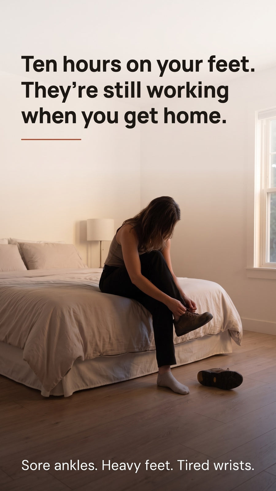 Person sitting on the edge of a bed taking off work shoes after a long day.
